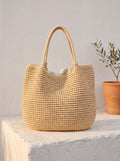 Bolso Duna de paja en beige, de pie sobre un poyete blanco