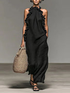 Vestido largo Elia en negro, de cuello halter y con volantes laterales, visto de frente