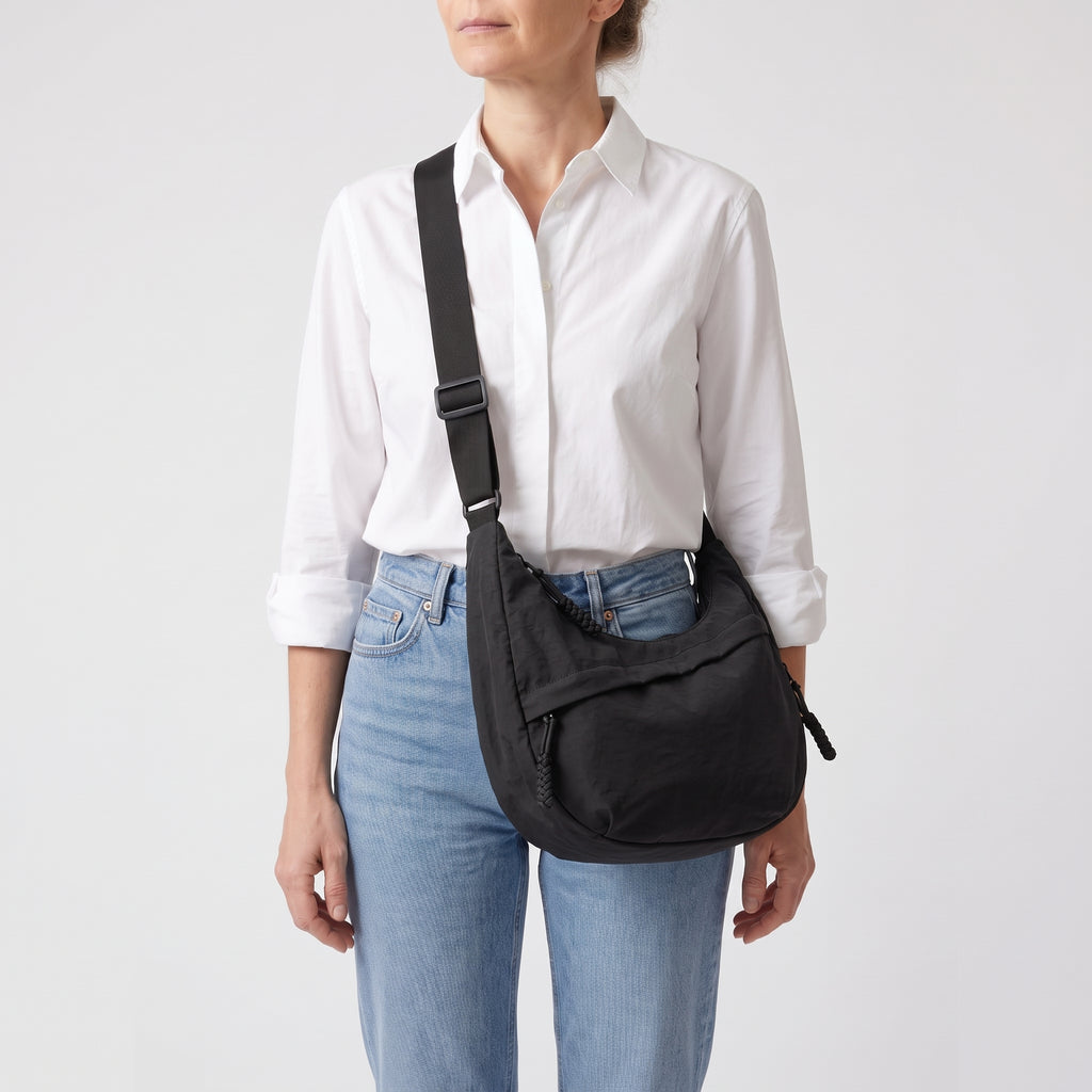 Mujer con camisa blanca lleva el bolso Nara negro cruzado por delante
