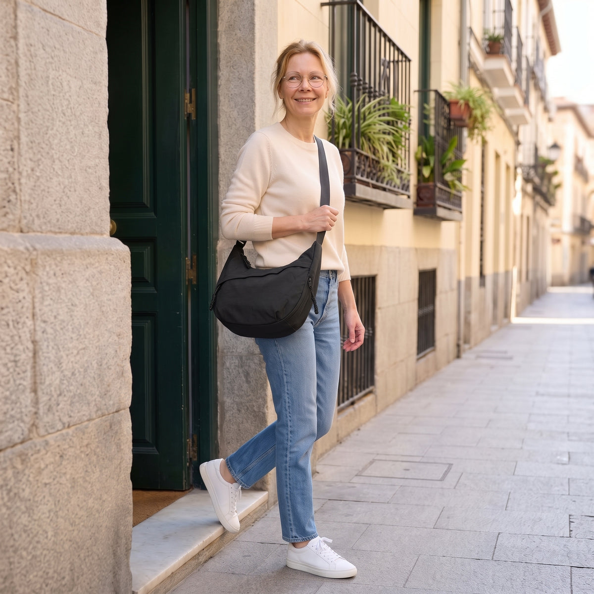 Mujer saliendo de un portal con el bolso Nara negro cruzado