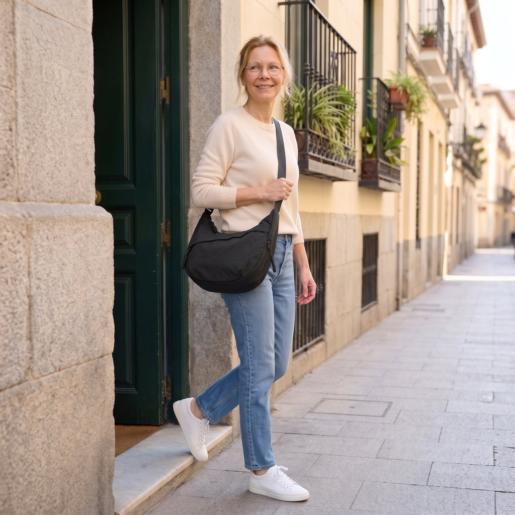 Mujer saliendo de un portal con el bolso Nara negro cruzado