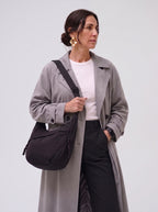 Mujer con gabardina gris y el bolso Nara negro al hombro, de frente