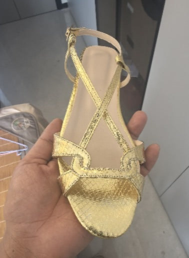 Sandalia plana dorada de tiras entrelazadas con nudo central