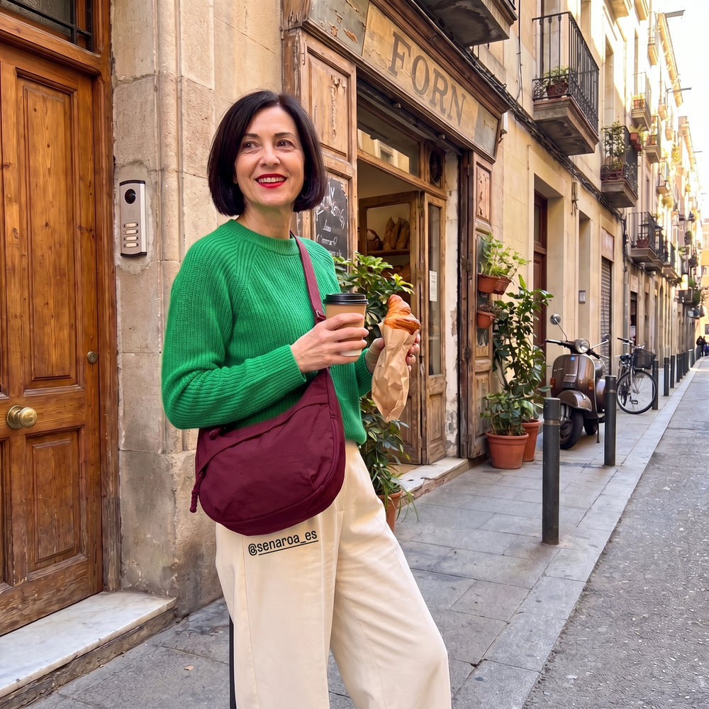 Clienta con jersey verde, café y cruasán, y el bolso Nara burdeos