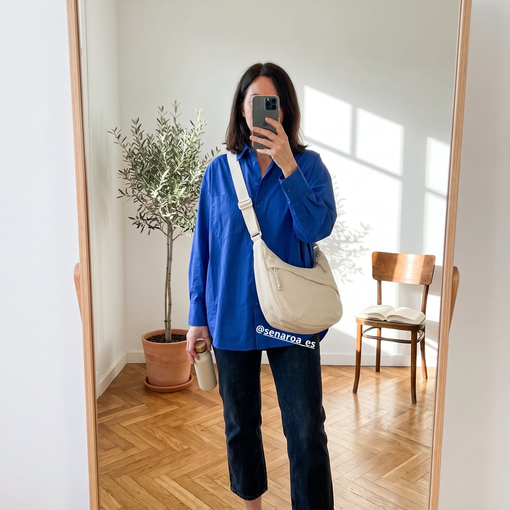 Clienta con camisa azul haciéndose una foto en el espejo con el bolso Nara crema