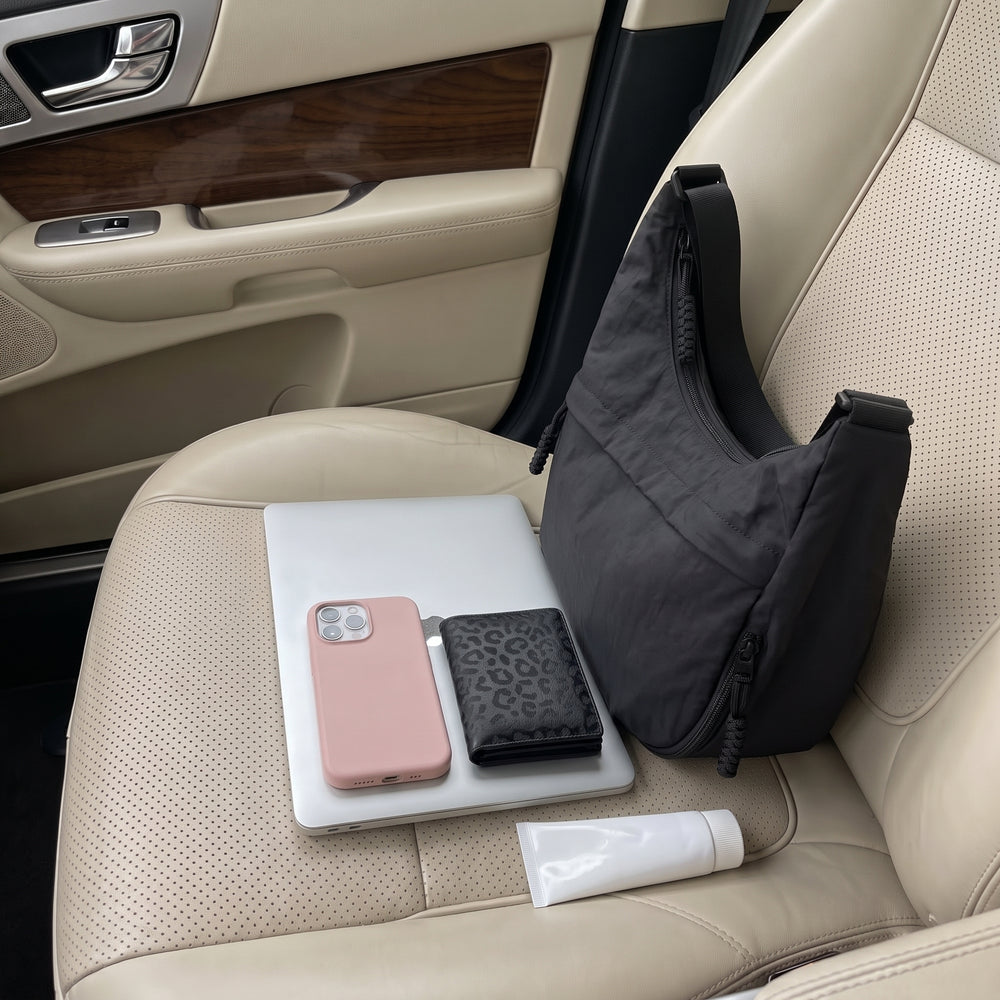 Bolso Nara negro en el asiento del coche junto al portátil