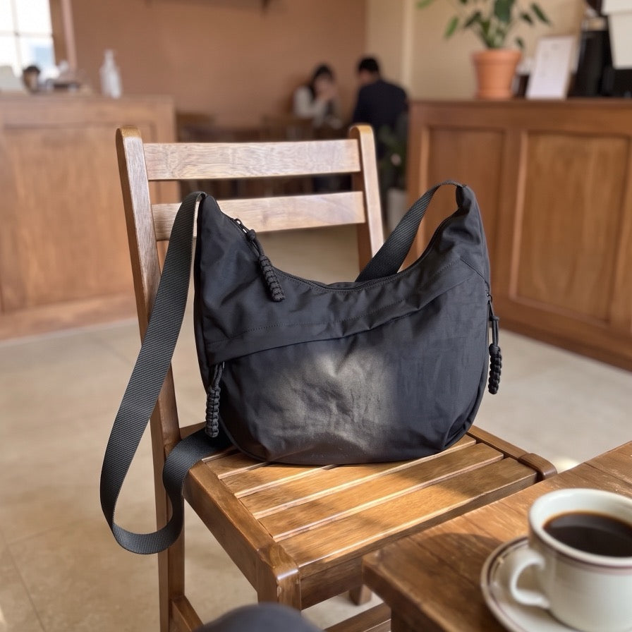 Bandolera Senaroa Nara en negro apoyada en una silla manteniendo su forma