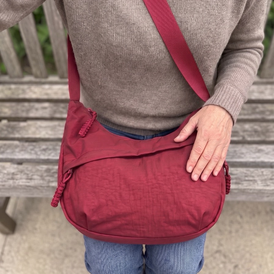 Bandolera Senaroa Nara en rojo apoyada en el regazo con la solapa frontal cerrada